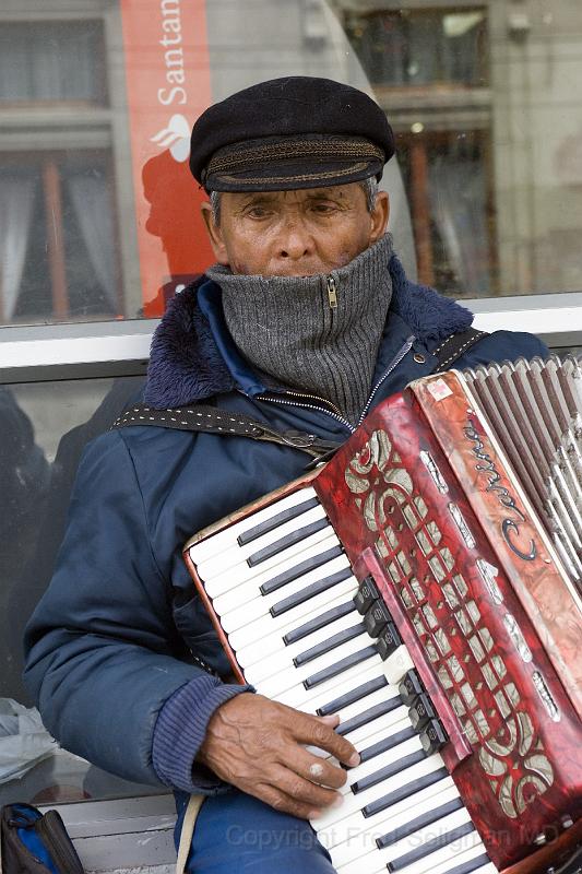 20071214 144159 D2X 2800x4200.jpg - Accordian Player, Puntas Arenas.  I gave him some money, then snapped some photos.  He remained expressionless throughout.  I have curiously observed this phenomina previously.  Mood inconsistent (flat and/or depressed) with the music being played